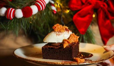 Dessert being held up in front of Christmas decorations covering the mantle piece in Gillies Restaurant