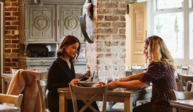 Two females sitting in a festively decorated Fratelli enjoying Christmas dinner