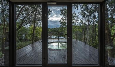 view through patio doors out onto glass enclosed patio and sunken spa, overlooking by woods and lough sunken spa