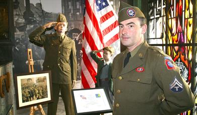 A man dressed up in a uniform from the Second World War standing in the gallery of the Northern Ireland War Memorial.