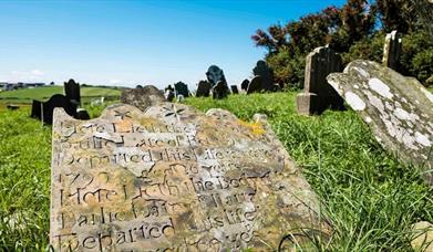 Close up photo of one of the gravestones, with others within view