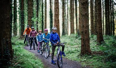 Family enjoy a cycle through woodlands at Gosford Park