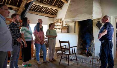 A group of visitors listening to the tour guide inside Andrew Jackson Cottage standing by the fire.