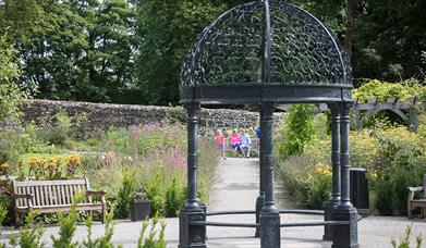 A couple and young child pictured through the arbour in Maghera Walled Garden.