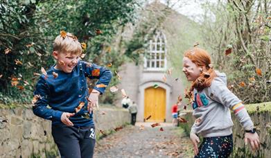 Children enjoying the autumn leaves in the museum grounds