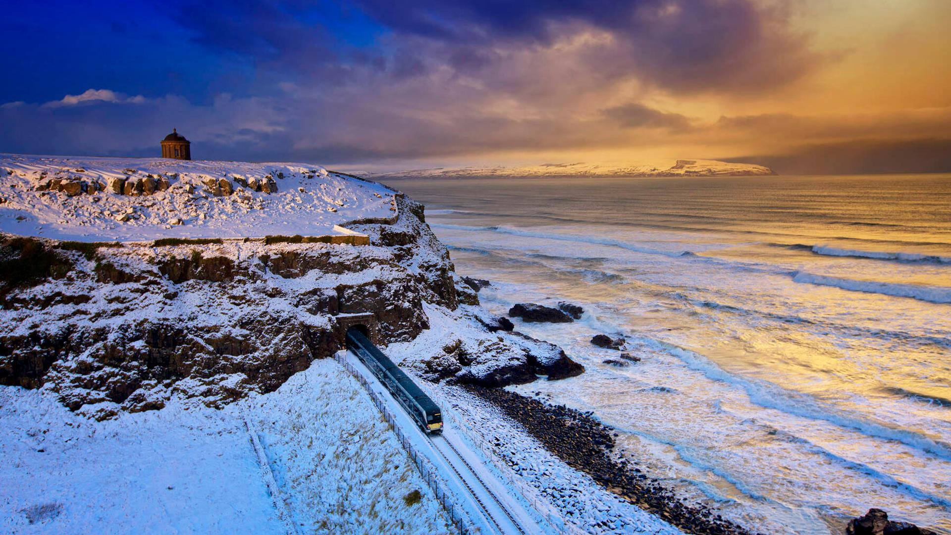 Snowy scene at Mussenden Temple with a train in the foreground