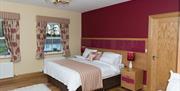 Image of a double bed in a room with a red wall and two bedroooms