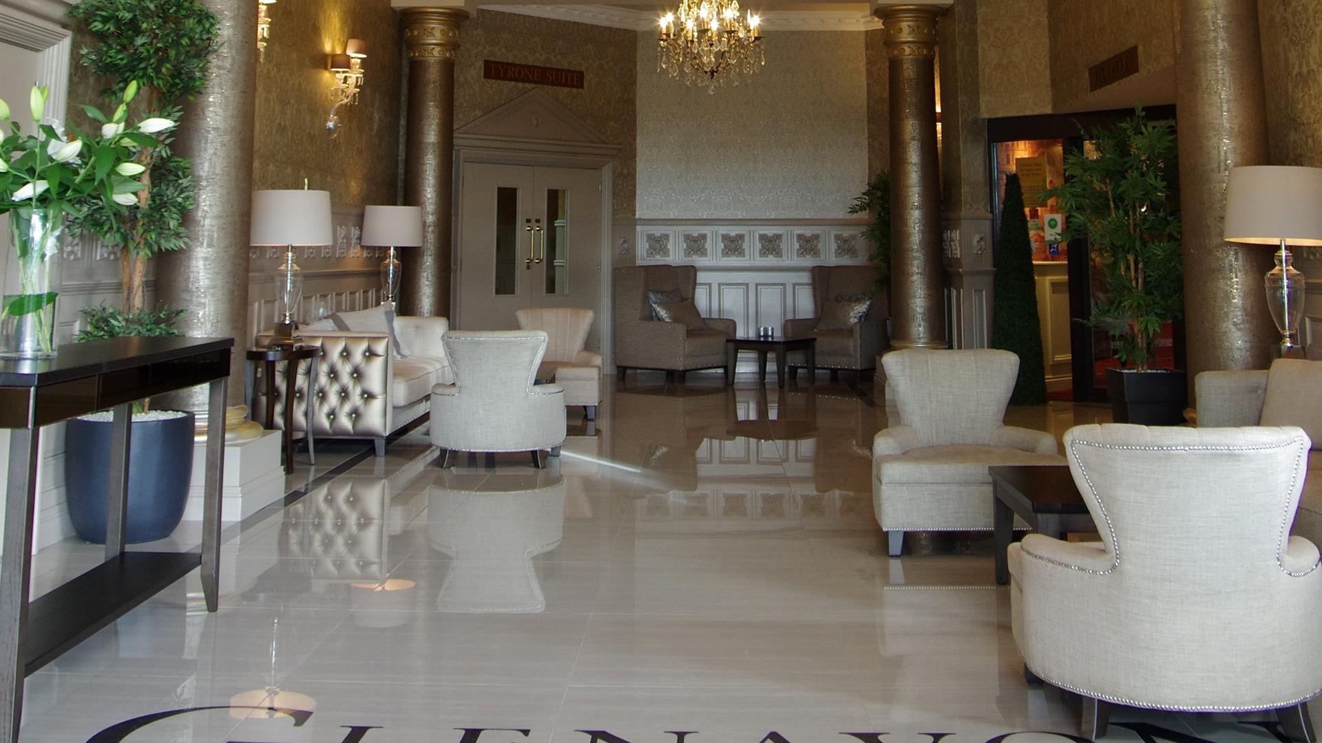 Image of the entrance hall with shiny tiled floors, cream armchairs, gold metallic columns and patterned wallpaper