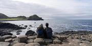 a couple look out to sea as they take in the views from the giant's causeway