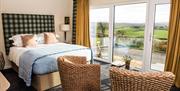 Shows image of double bedroom with 2 chairs and view of the countryside