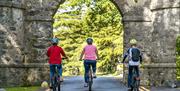 3 Cyclists entering the beautiful stone archway entrance of Tollymore Forest Park