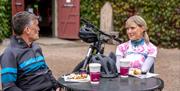 2 cyclists enjoying coffee and scones in the courtyard of Castle Ward