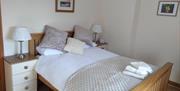 Double bed with white lined, Textured throw and lilac cushions