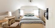Double bedroom with cream wooden furniture which includes table, dresser, bedside lockers and chest of drawers