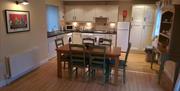 Image shows kitchen/dining area with table and chairs. Also wooden floor