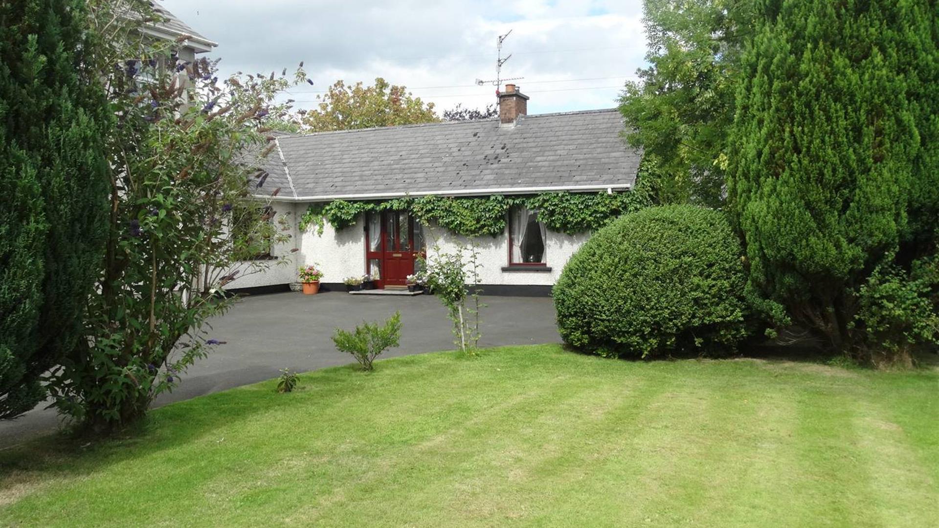 Outside of cottage, garden and trees in image