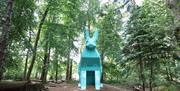 An image of Peep the Hare part of the digital sculpture trail, the hare is teal and is located in the forest park.