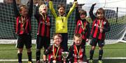 Group of children with medals and trophies after a successful football match
