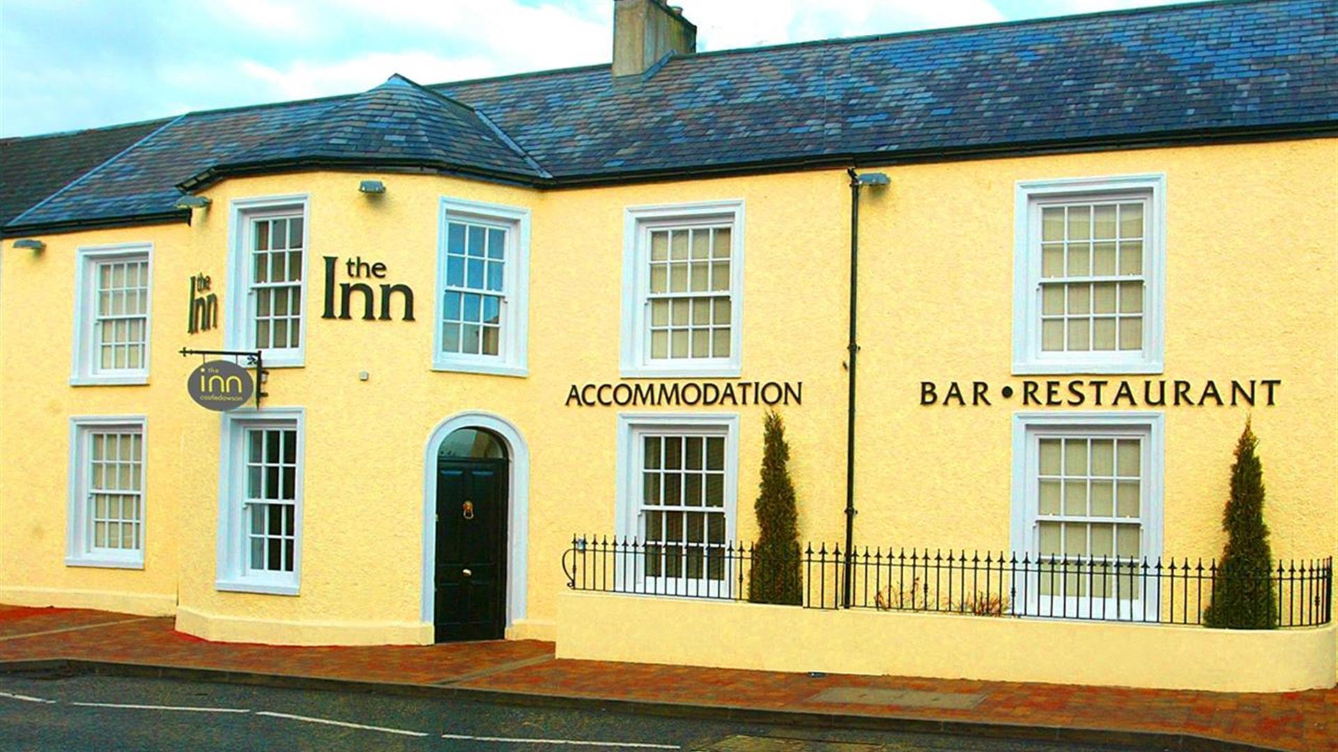 Outside image of The Inn with yellow walls and a black door