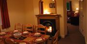 Cosy dining room with a lit fire and table set for eight people