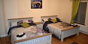 Bedroom with two double beds which have floral bedding and green curtains