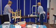 Two ladies, both painting a wooden chairs