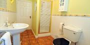 Image shows tiled bathroom with shower, sink and toilet