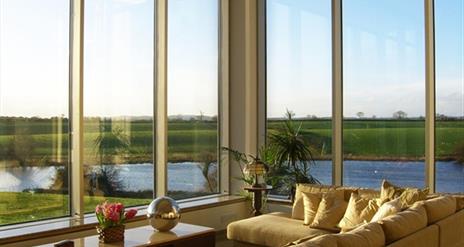 Photo of living room area which has large windows showing views of the surrounding pretty landscape
