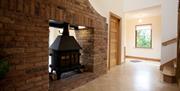 double sided stove in brick fireplace in living area and entrance hallway
