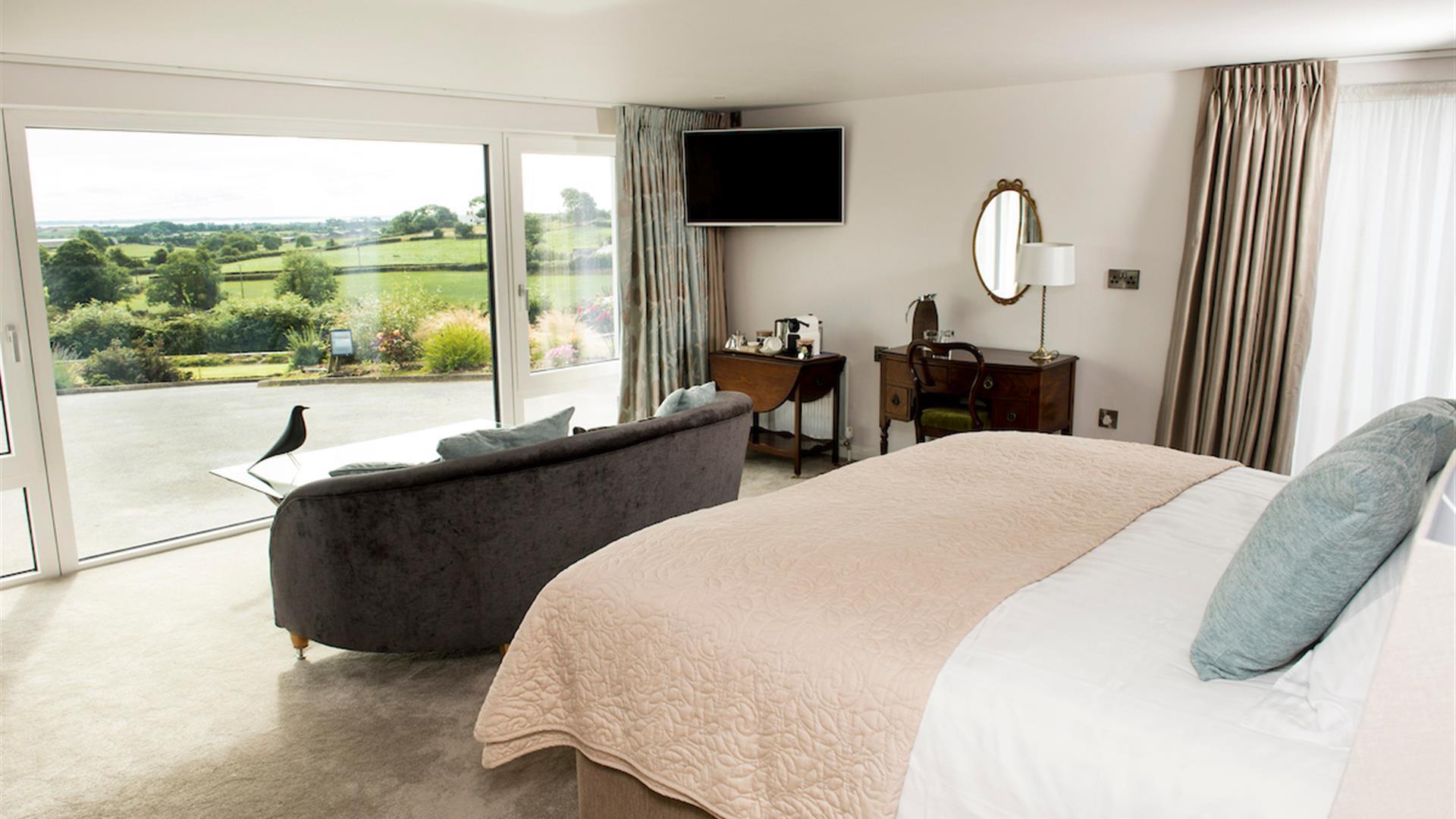 Shows image of double bedroom with large window looking out at countryside view