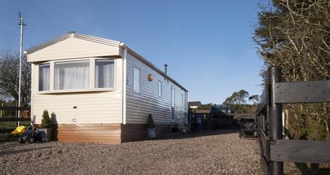 Image of the exterior of a static caravan and a stoned driveway