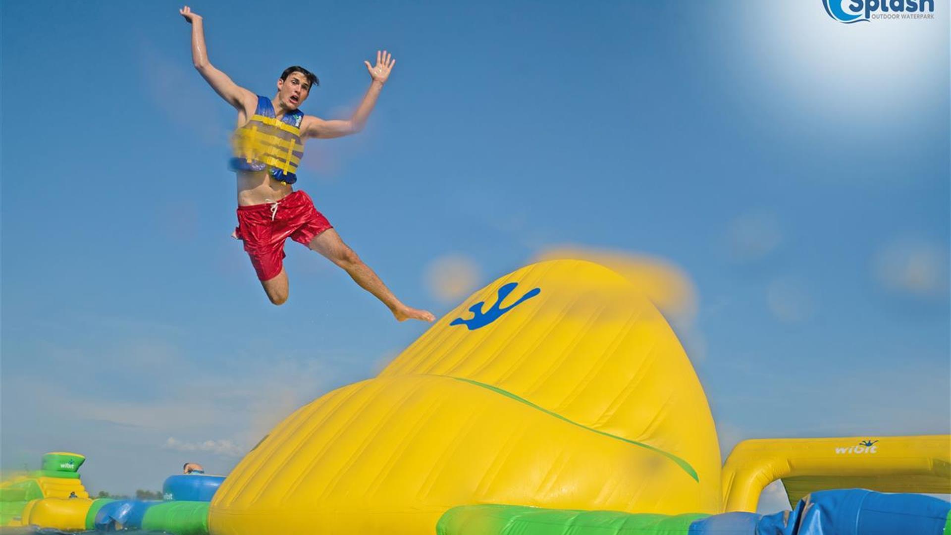 Boy jumping off a large inflatable into water