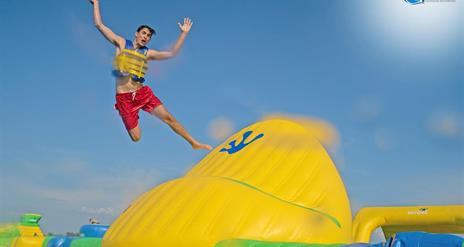 Boy jumping off a large inflatable into water