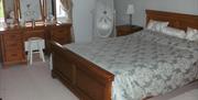double bed with long standing mirror and wooden dresser with chair and mirror