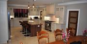 A large open plan kitchen with island unit and dining table