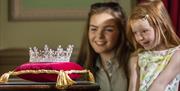 Image is of woman and child looking at a crown on a cushion