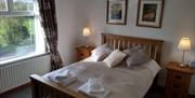 Wooden double bed with a textured throw and coloured coloured pillows