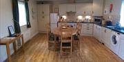 Image shows large kitchen/dining area with table and chairs. Wooden floor.