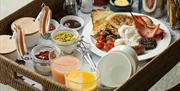 Shows image of breakfast tray filled with cooked breakfast and juices