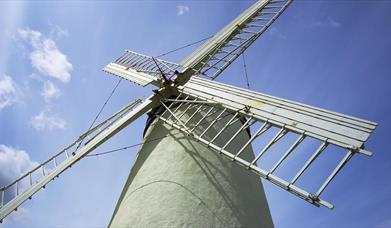 a photograph looking up at a windmill with a blue sky in the background