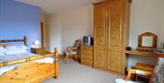Double bedroom with wooden furniture including, wardrobe, bedside lockers, dresser with mirror