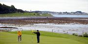 Photo of two golfers in play with stunning scenery to the background