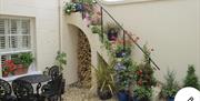 Courtyard showing beautiful potted plants carrying up a stairwell and seated area beside it