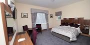 A large bedroom with double bed, table, two chairs, desk and mirror