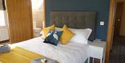 double bed with yellow cushions and folded towels and toiletries on top