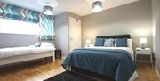 Triple bedroom with navy and white double bed and white single bed