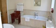 Image shows bathroom with bath/shower over bath, sink and toilet