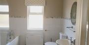 Tiled bathroom with bath, sink and toilet