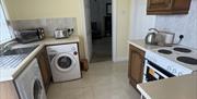 Utility room showing washing machine, tumble dryer, cooker, toaster, kettle, waffle and toastie maker.