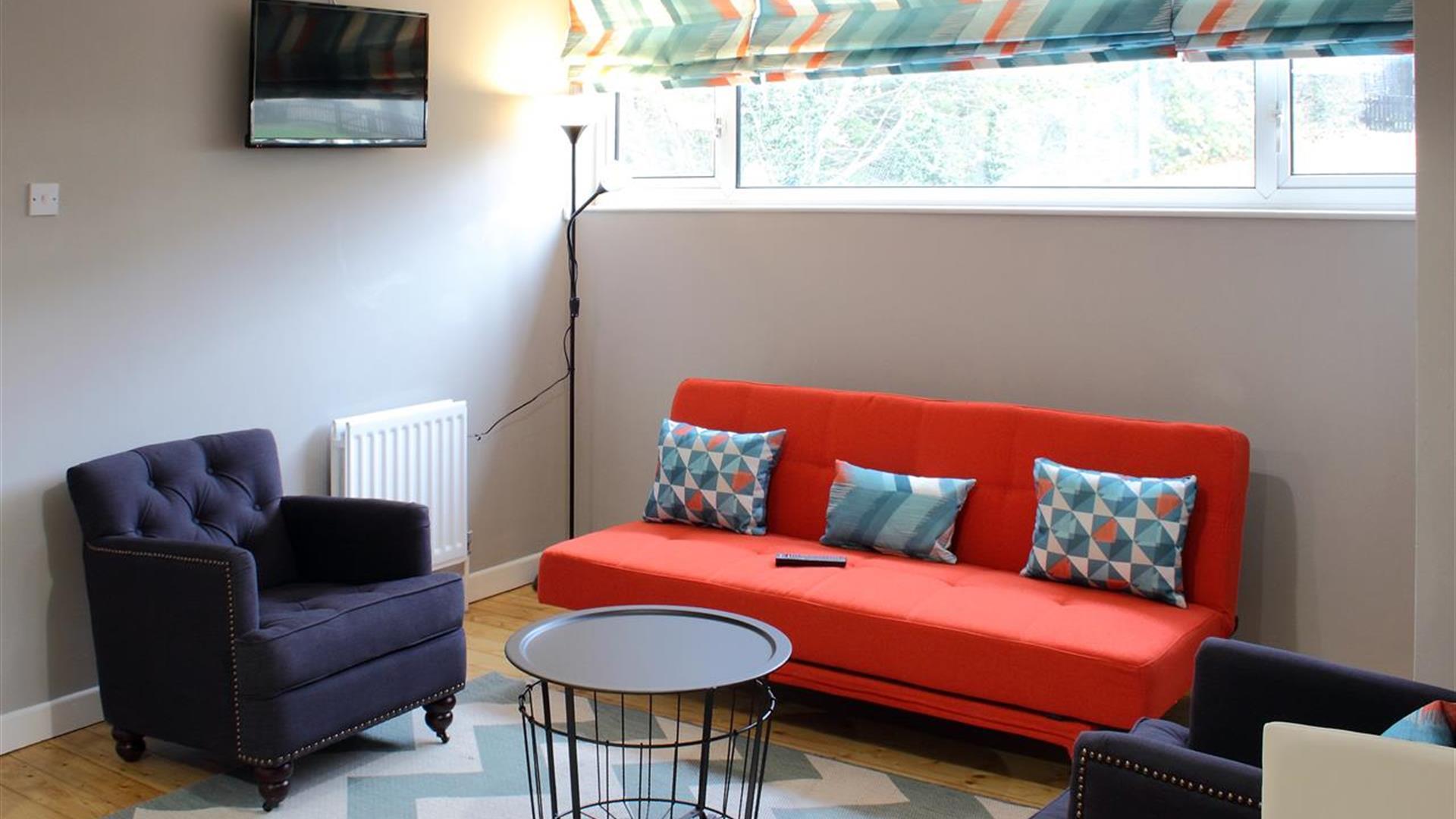 living area with orange sofa and 2 navy armchairs